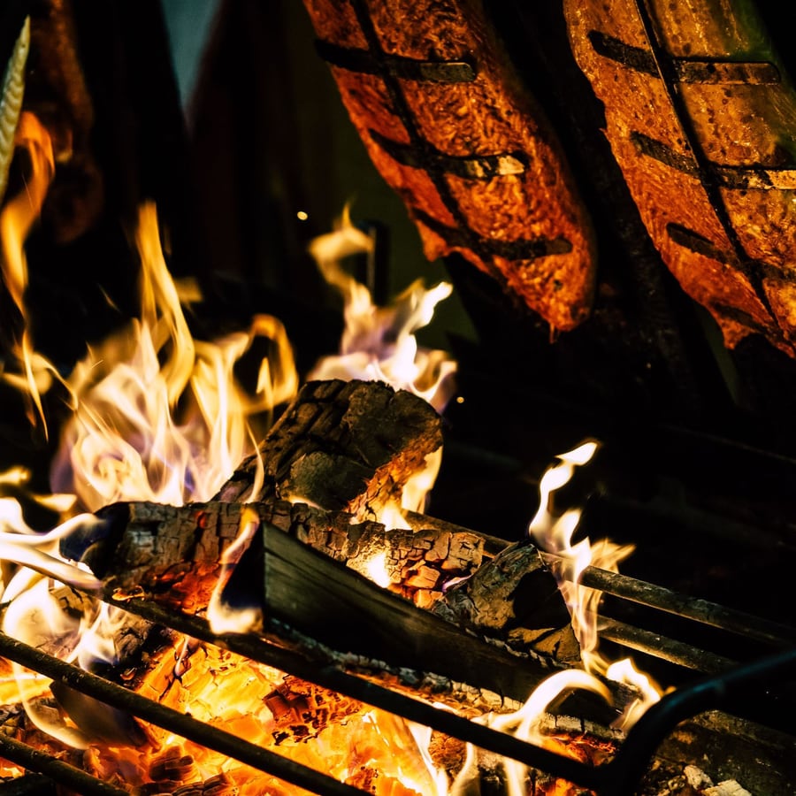 Poissons entiers ouverts, en cuisson au-dessus des flammes.