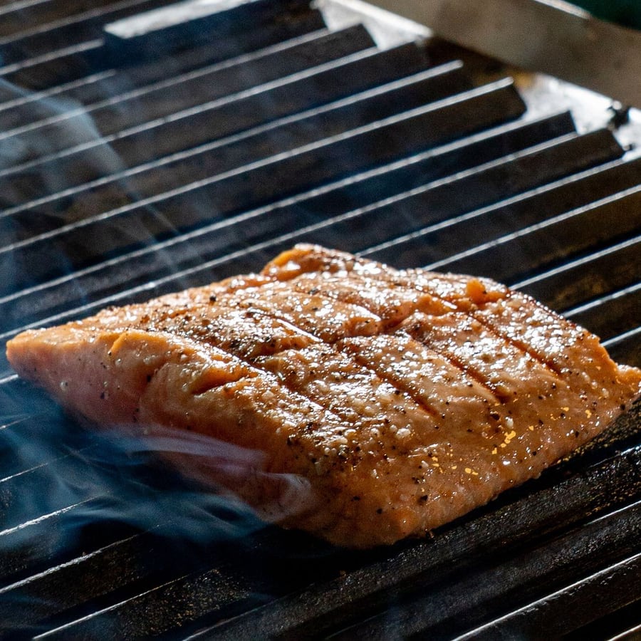 Pavé de saumon sur la grille, dans la fumée.