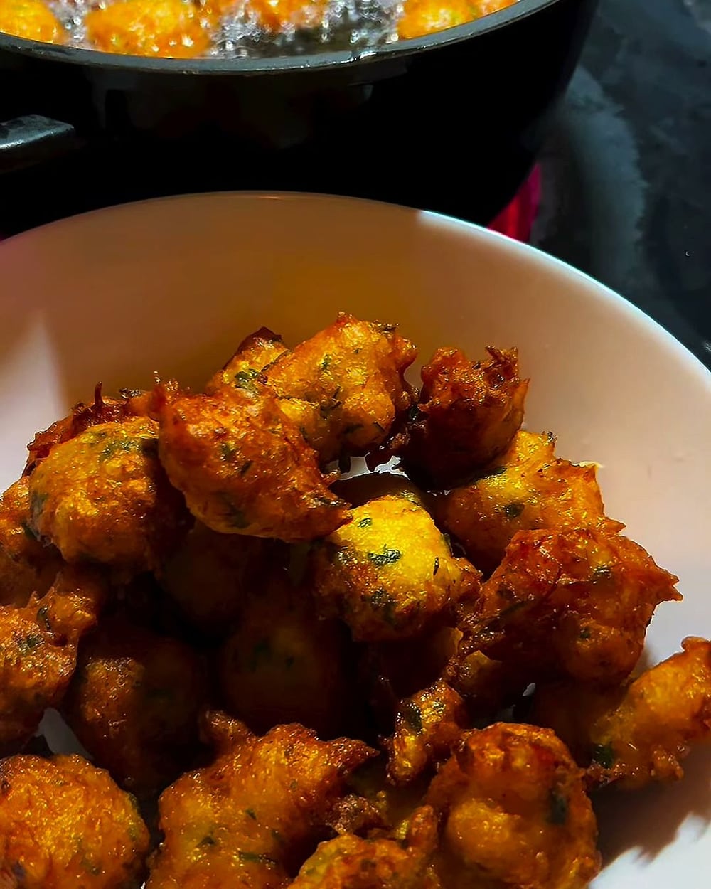 Bol d’accras dorés, la poêle de friture encore derrière.