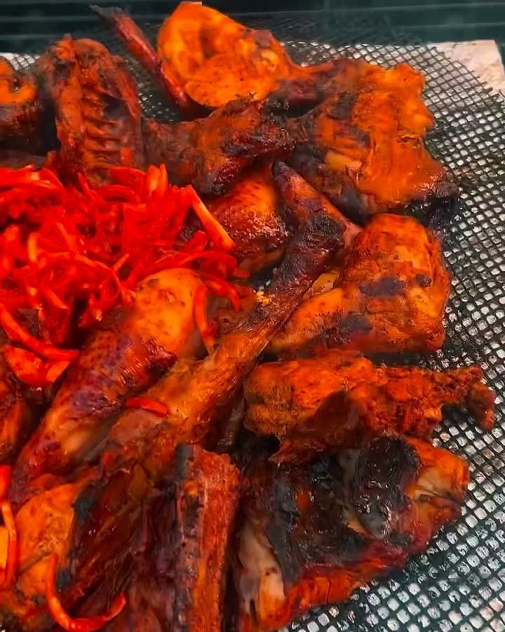 Bac de morceaux de poulet marinés au paprika, avec des carottes râpées.
