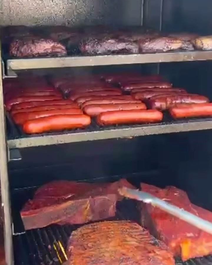 Les grilles du smoker chargées : travers en haut, saucisses au milieu, grosses pièces en bas.