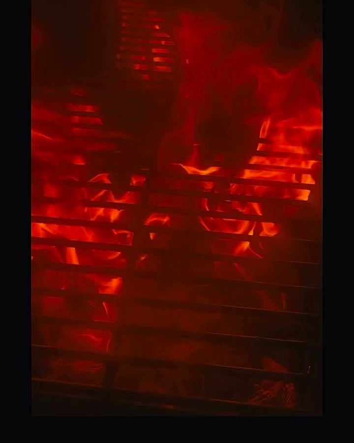 L’intérieur du smoker éclairé de rouge, grilles vides avant l’enfournement.